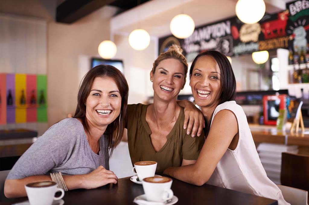 Group of laughing women friends in coffee house